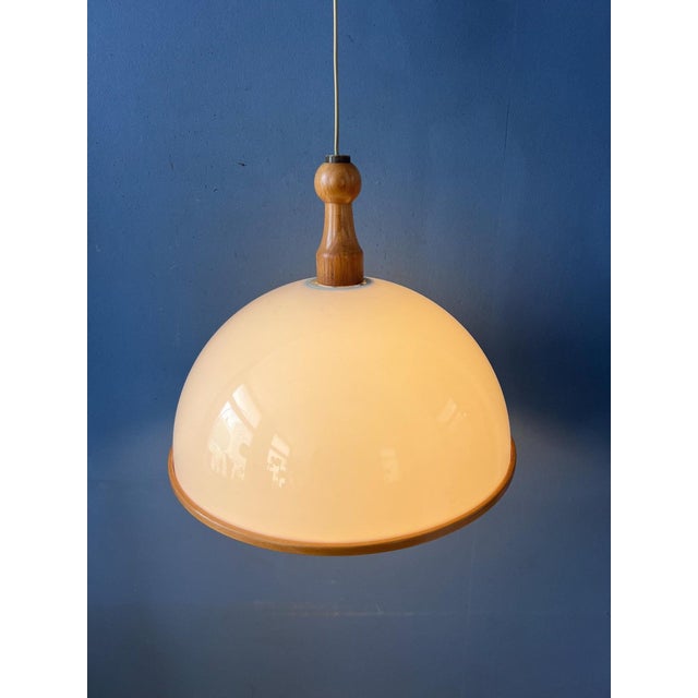 Vintage Steinhauer pendant lamp featuring a white acrylic glass dome shade combined with warm wooden elements, creating a...