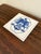 A classic Dutch Delft-style hand painted blue and white porcelain tile featuring an intricately rendered heraldic coat of...