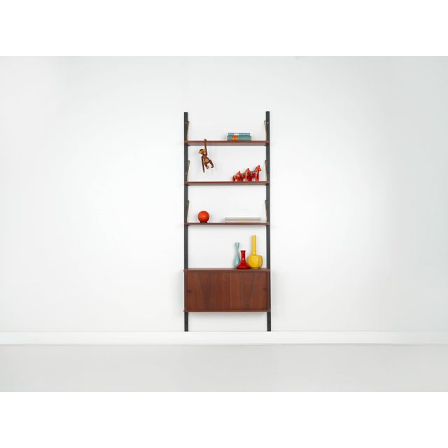The modular shelving unit was manufactured in the 1960s in Denmark. The structure is covered with teak veneer. The surface...