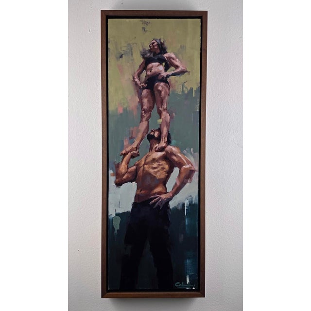 The artwork depicts a striking moment of balance and trust between two figures, with a strong male figure supporting a...