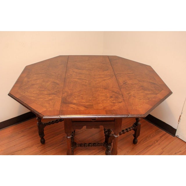 A vintage William & Mary style breakfast table with an octagonal burial wood top, drop leaves, single drawer and ring and...