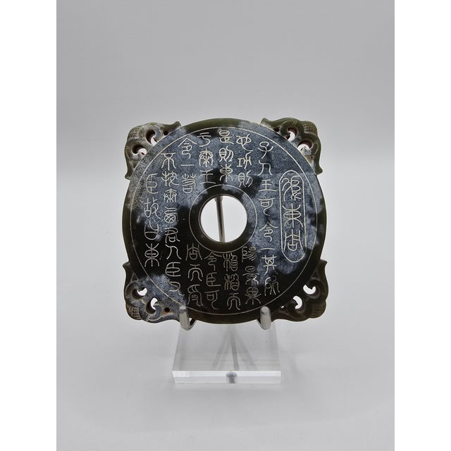 Striking nephrite jade ornament carved in a classic bi disc form with a center aperture, openwork corner scrolls, and an...