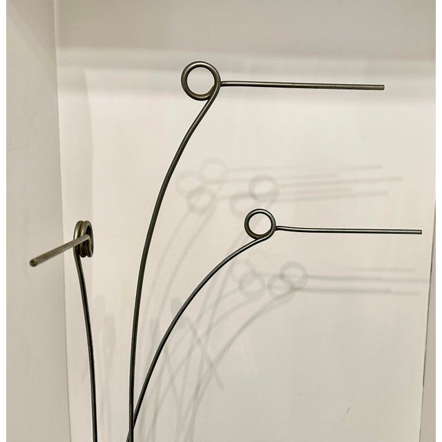 A contemporary abstract metal sculpture featuring hand-formed steel rods rising from a rectangular base. Each element...