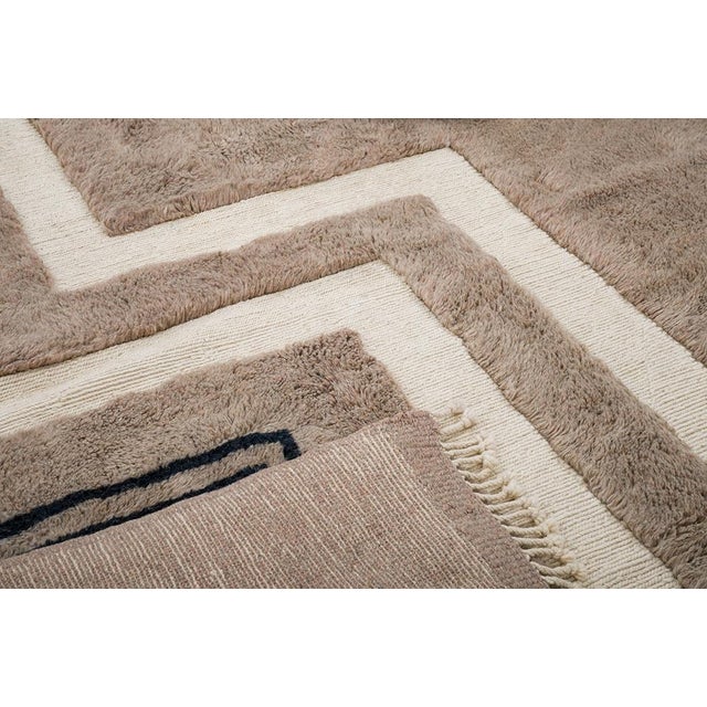 Bold lines, bent at sharp angles, tracing a path across taupe. Two thick ivory bands zigzag downward across a rich taupe...