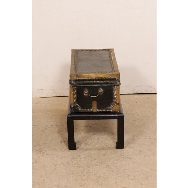 A Chinese leather-wrapped wooden trunk with brass and nail-head accents from the 19th century and raised on a vintage wood...