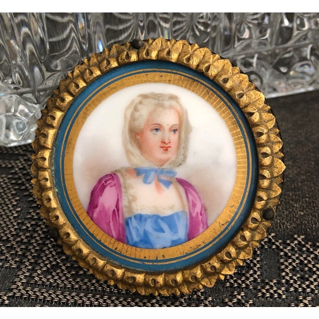 This very unique small hand painted French Woman's portrait. The painting is on a porcelain disk with hand painted gold...