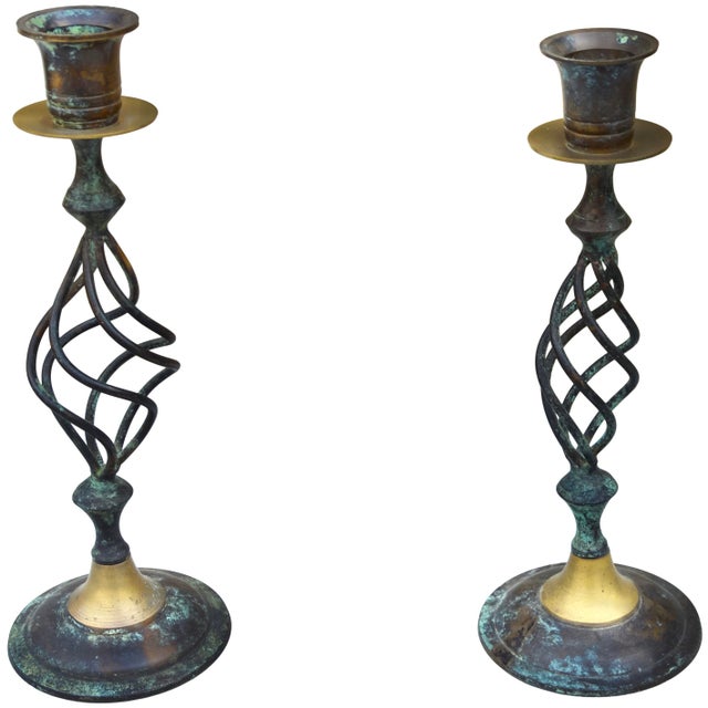 Striking midcentury pair of candleholders meticulously handcrafted of solid brass and metal. Featuring ornate playful...