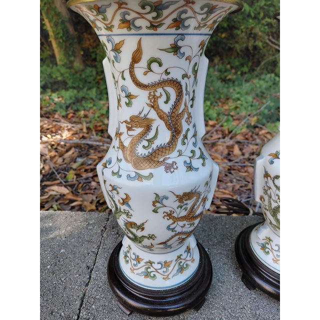 Striking pair of vintage Asian-style porcelain table lamps featuring colorful hand-painted dragons, scrolling clouds and...