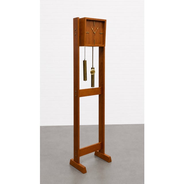 Mid Century Modern Floor Clock featuring a solid teak case with minimalist brass accents and a sculptural open frame...
