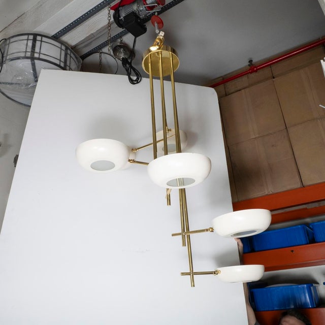 Stilnovo style stepped brass chandelier featuring enameled metal shades with frosted frosted diffusers.