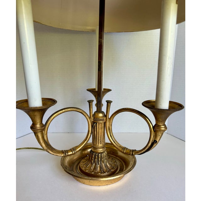 This elegant early 20th century brass bouillotte lamp features a classic French-inspired design with three gracefully...