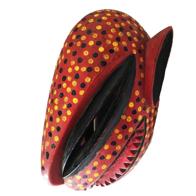This intricately carved and colorfully painted mask is a stunning representation of a Leopard, with its vibrant red...