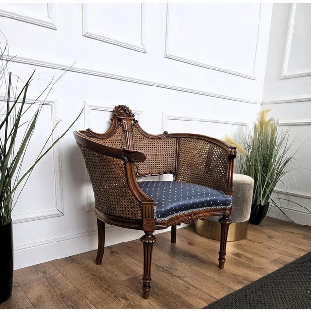 Very decorated armchair in wood and cane with classic blue and gold upholstery. The design and shape of the wooden...