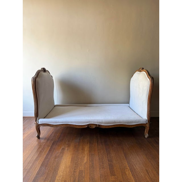 A European walnut daybed from 1880 featuring a finely carved frame and new cream velvet upholstery. Both timeless and...