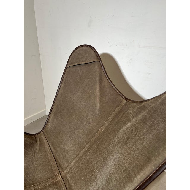 Classic butterfly chair featuring a grey canvas sling seat supported by a sleek black powder-coated iron frame. A timeless...