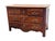 A French walnut commode with molded drawer fronts and shaped paneling, fitted with three drawers and ornate brass pulls....