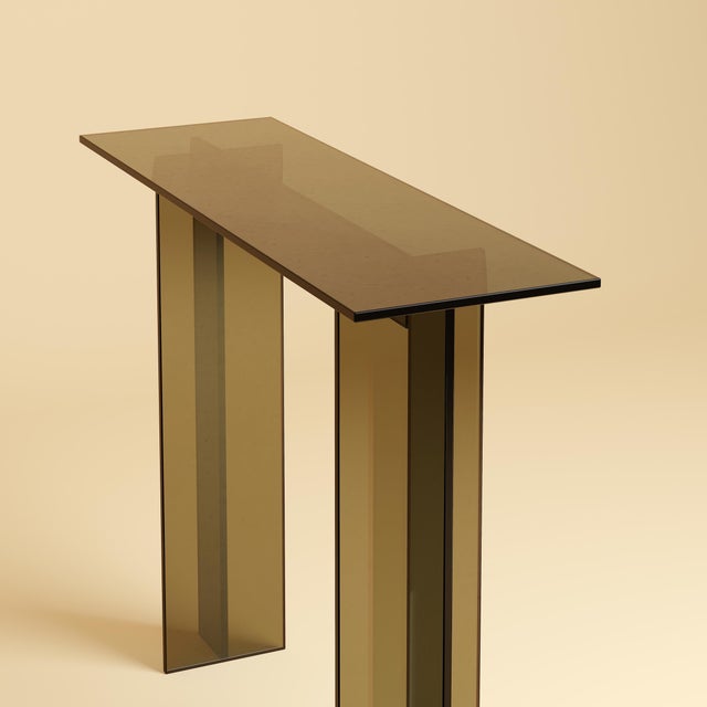 The Naz is a bronzed glass console table, a study in transparency built from Italian glass rather than stone. It trades...