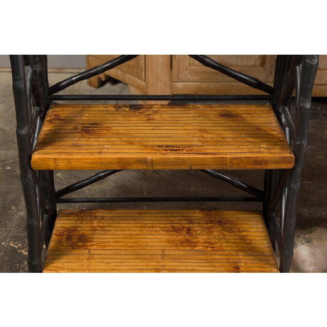 A pair of French tall shelves from the Midcentury period, with black faux-bamboo structure and brown shelves. A stylish...