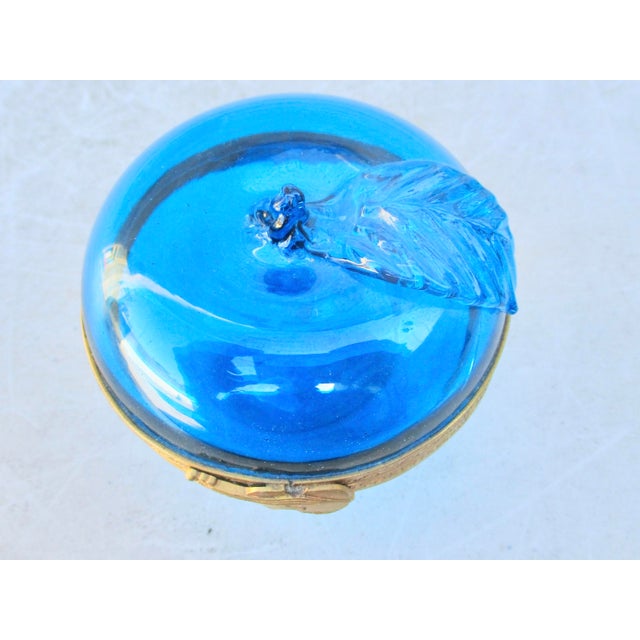 Cobalt blue glass apple box with gilt brass rims, snap is a violin. Hinged top. The apple has a single leaf and a hand-cut...