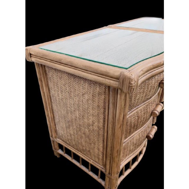 A pair of 3 drawer wicker nightstands in a natural tan color. The nightstands feature 3 smooth track drawers with pretty...