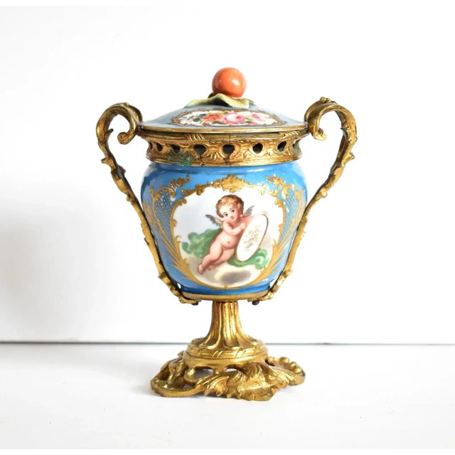 An antique, 19th-century French porcelain urn or lidded vase, with a "bleu celeste" background and medallions of a cherub...