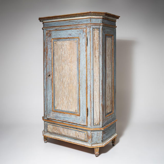 Single-door Louis XVI cabinet with fluted paneling, chamfered corners, and a drawer in the base section. The cornice is...