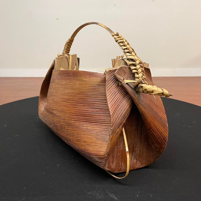 A rare handcrafted water carrier from Papua New Guinea, created using dried palm leaves and cane. The folded palm...