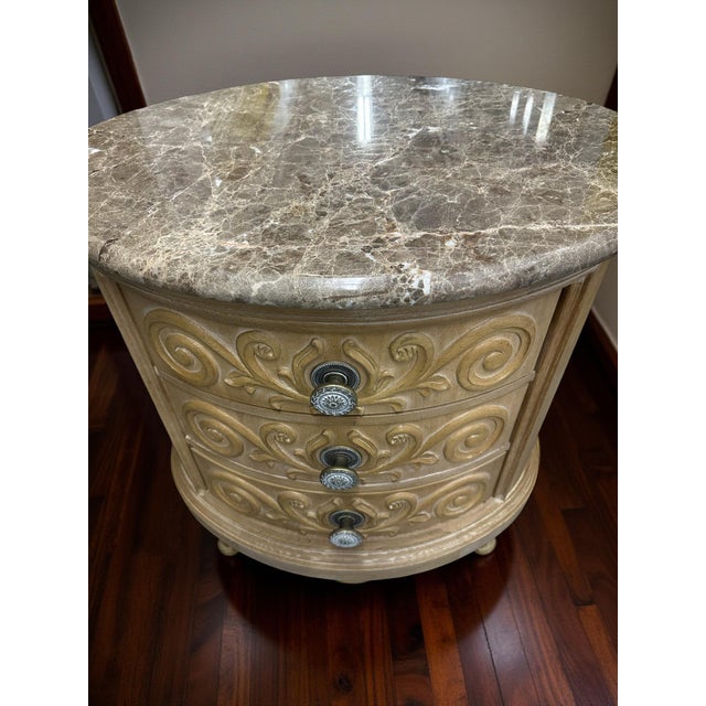 A stunning and rare round marble-top chest featuring a beautifully carved three-drawer design and luxurious solid marble...