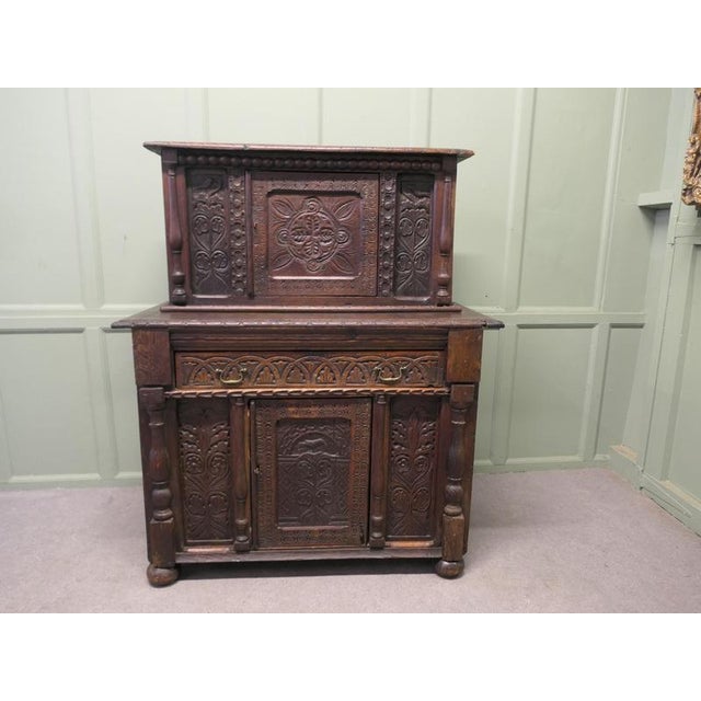 This is an old and charming piece of carved oak furniture, the top section has a single cupboard enclosed by 1 carved...