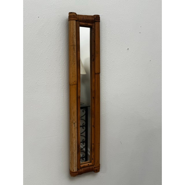 This vintage slender vertical wall mirror features an authentic frame handcrafted from thick stalks of natural tan bamboo....