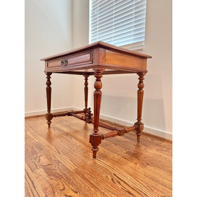 Antique French Louis XVI style writing table in warm-toned fruitwood, likely cherry. The table has a rectangular paneled...
