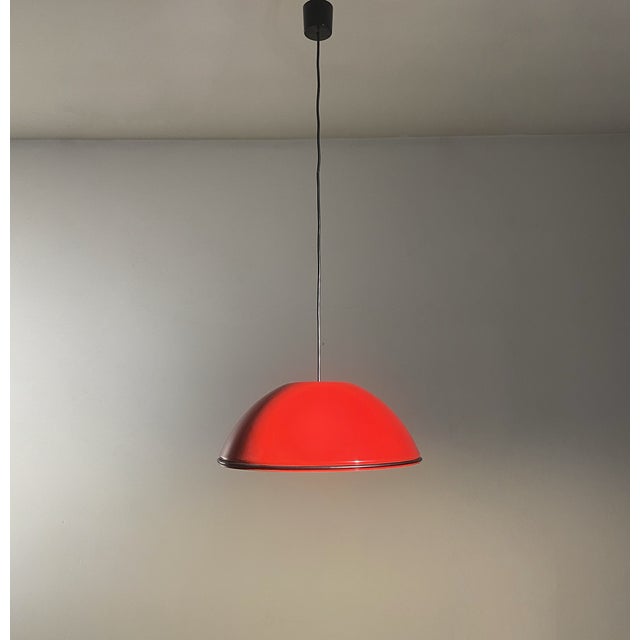 Vintage pendant lamp, with polished metal lampshade, red on the outside and white on the inside. Around the red diffuser...