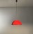 Vintage pendant lamp, with polished metal lampshade, red on the outside and white on the inside. Around the red diffuser...