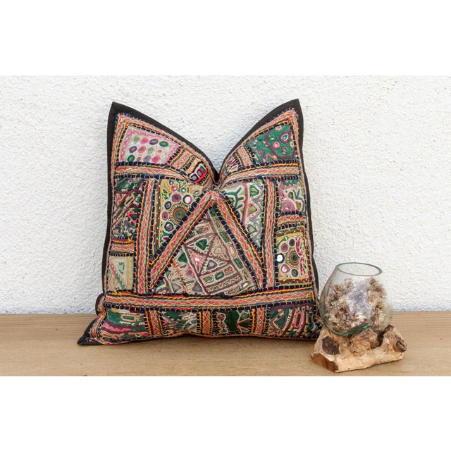 This 16-inch square pillow is a breathtaking fragment of Rajasthani heritage, repurposed from antique Banjara...