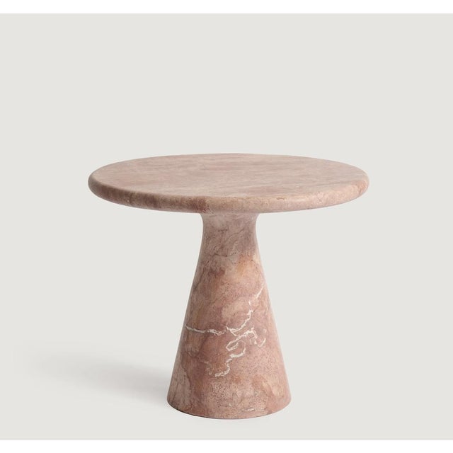 This minimalist table is crafted from Red Travertine showcasing a circular tabletop that balances securely and...