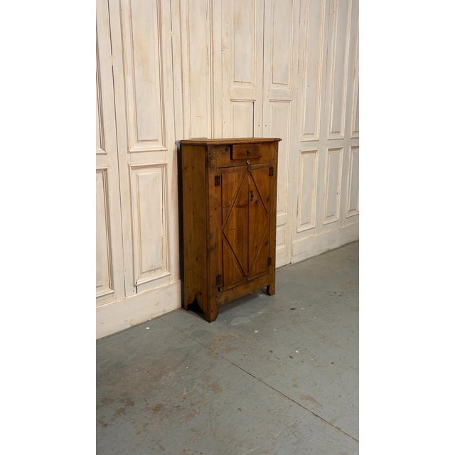 A 19th-century fir cabinet featuring two doors with elegant mirrored diamond workmanship and a practical drawer. A piece...