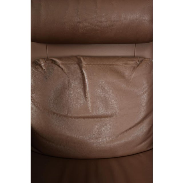 This modernist armchair with a rectangular footstool was manufactured in Denmark during the 1970s. The set is upholstered...