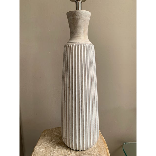 A ribbed wooden, white washed table lamp. The lamp is made in neutral, natural colors of turned wood, which makes for a...