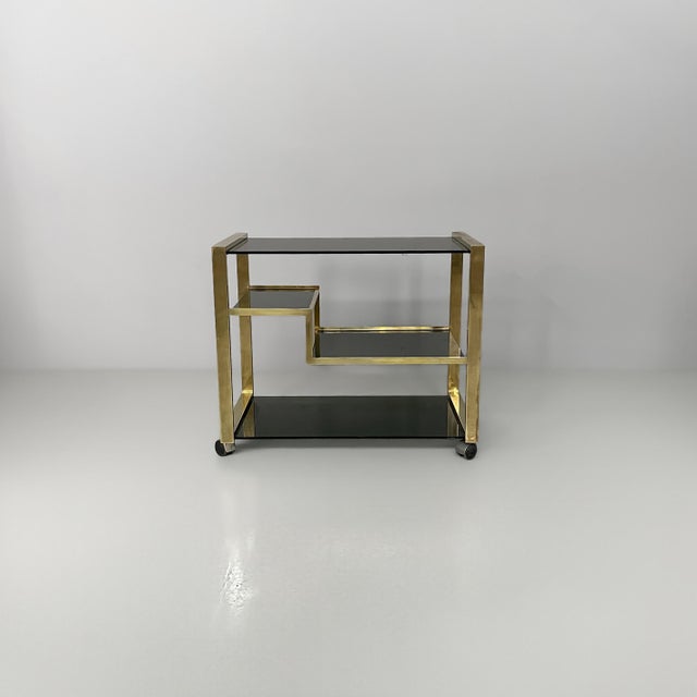 Italian modern brass and smoked glass cart, 1970s Cart with a brass frame and smoked glass shelves. The geometric...