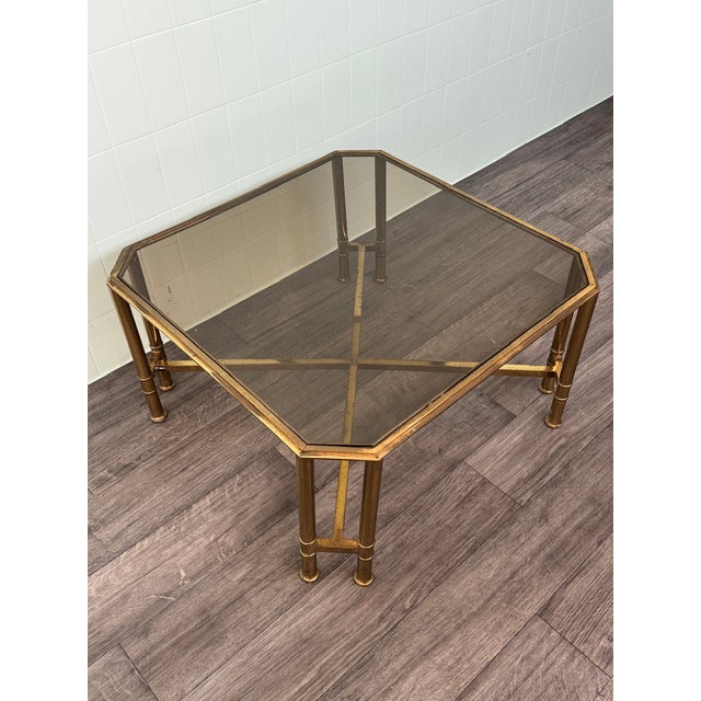 Vintage Hollywood Regency-style coffee table dating back to the 1960s or 1970s. The frame is made of brass, and the top is...
