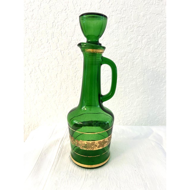 Lovely Italian transparent glass handled decanter in Emerald green featuring 24 karat gold embellishments in a grapevine...