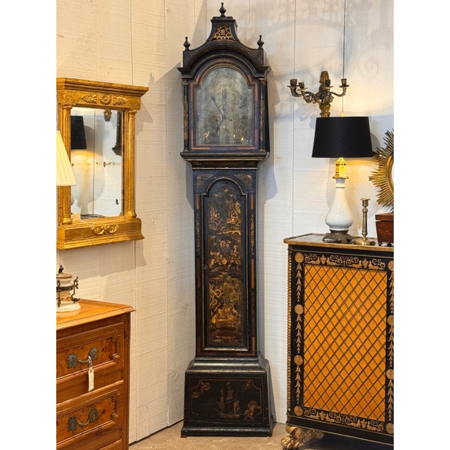 An 18th century English longcase clock with chinoiserie decoration on a black lacquer ground, featuring gilt figures,...