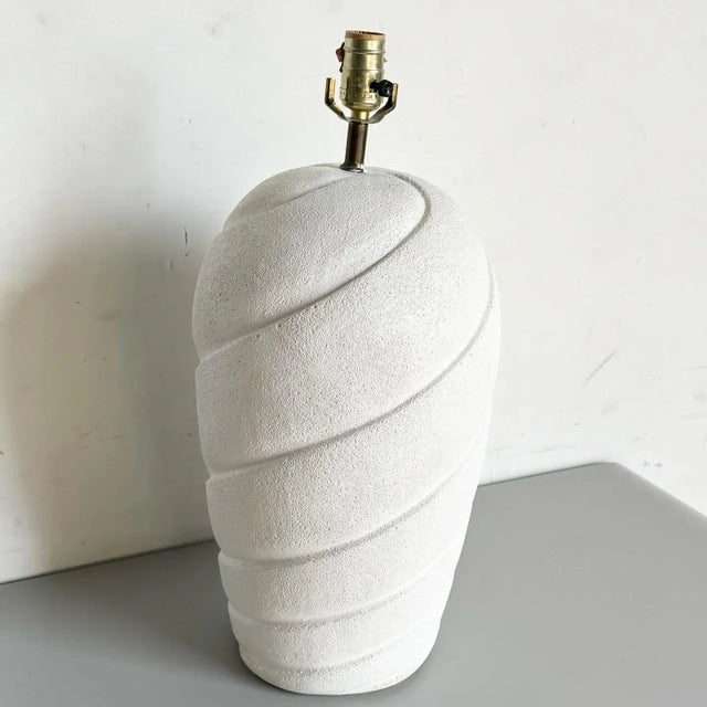 Illuminate your space with this striking Postmodern Off White Sculpted Swirl Ceramic Table Lamp. This lamp features a...
