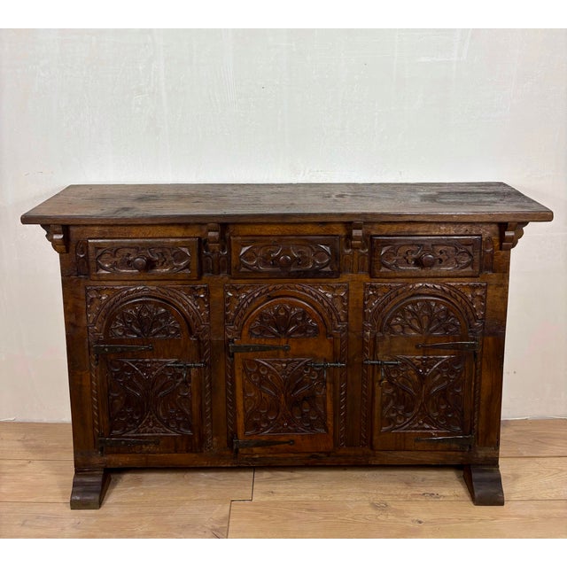 Striking Spanish sideboard cabinet crafted in solid oak, featuring rich hand-carved decoration throughout the façade. The...