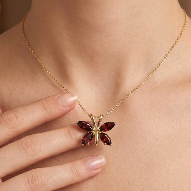 The wings are artfully adorned with four deep, rich, and lustrous natural garnet gemstones. The intense, fiery red hues of...