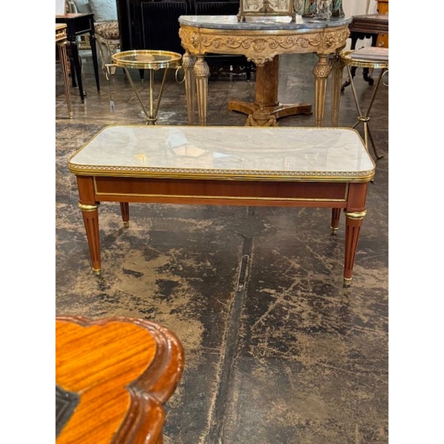 Handsome French Louis XVI style mahogany and marble coffee table. Featuring a beautiful wood finish, gold gilt details and...