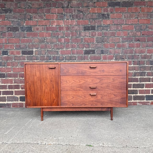 Jens Risom Mid-Century Modern walnut cabinet featuring beautifully figured walnut and sculpted wood pulls. The cabinet...