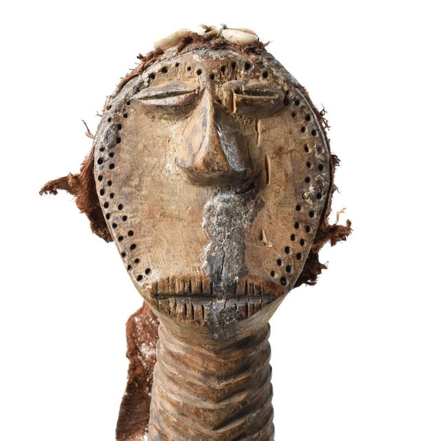 The Songola figure was hand-carved by the Songola people of Congo. This unique piece has cowry shells attached to the...