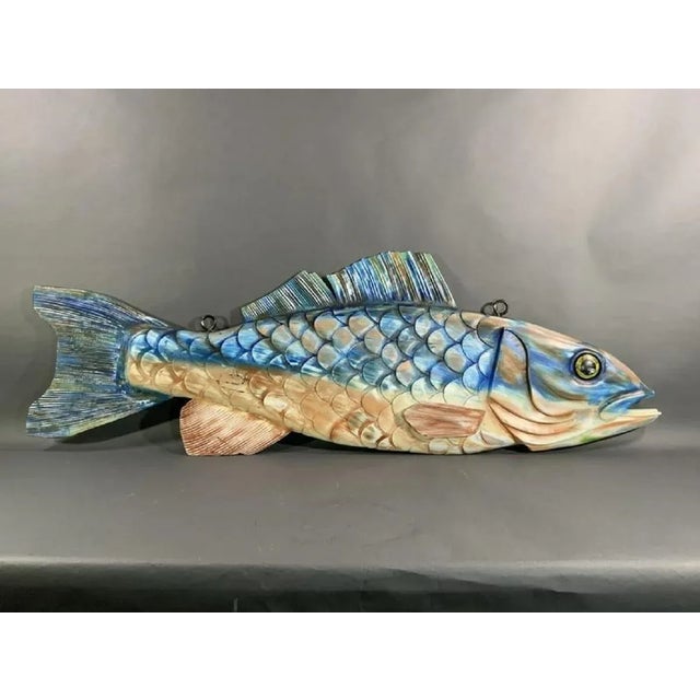 Intricately carved hanging wood fish. Carved with gills, eyes, fins etc. Colorfully painted in blues and cream. Overall...