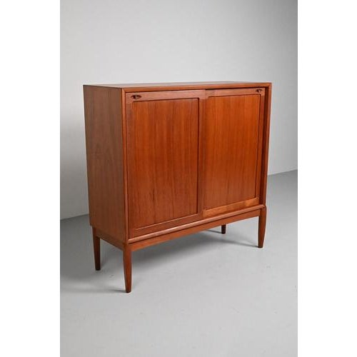 Cabinet from h.w. Klein for bramin. Made in germany in the 60’s. This teak and teak veneer cabinet has sliding doors...